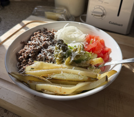 Healthy burrito bowl with ground beef, fries, and fresh toppings